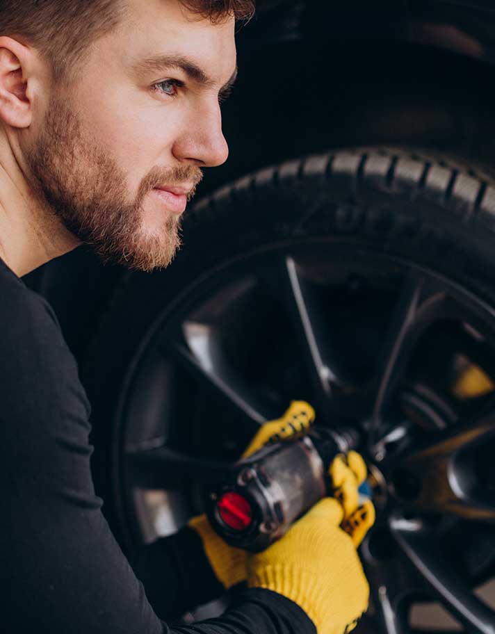 A man holding a tire with a wrench in his hand.