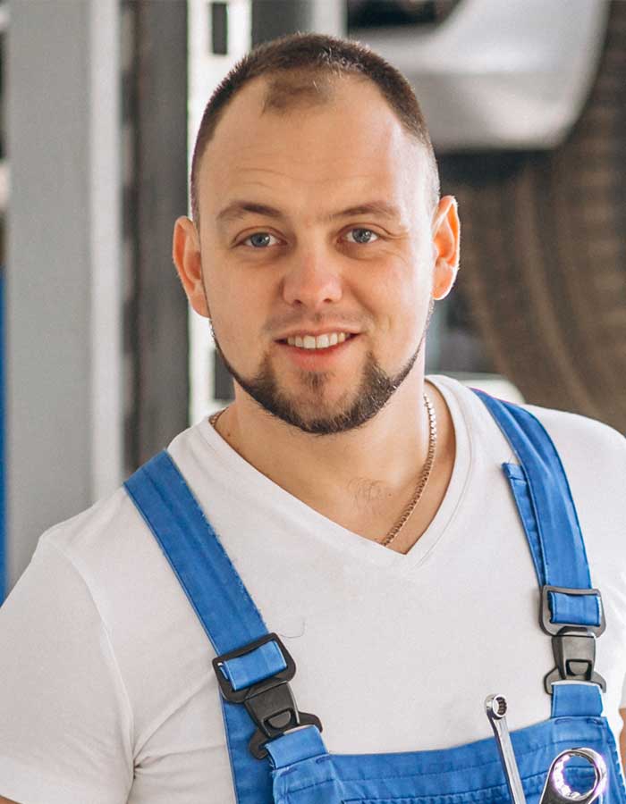 A man with blue suspenders standing in front of a building.