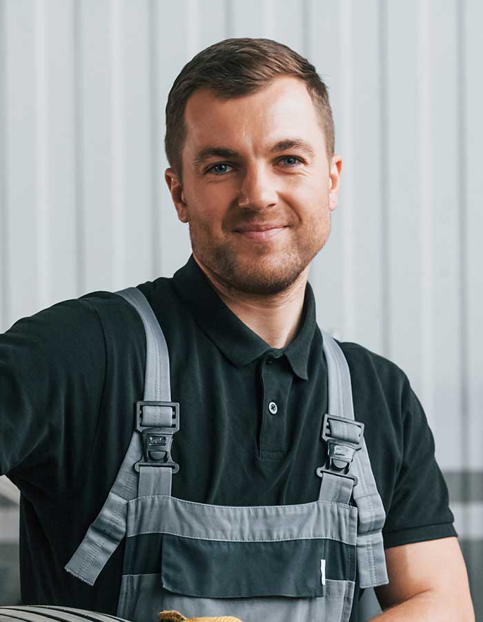 A man in black shirt and gray overalls.